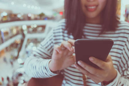 Woman hand using smartphone and smile feel fun with nature beautiful background. Business, financial, trade stock maket and social network concept.の写真素材