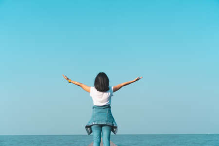 Woman rise hands up to sky freedom concept with blue sky and summer field background.の写真素材