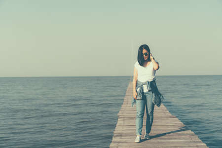 Womanis walking alone freedom concept with blue sky and summer field background.の写真素材