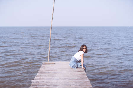 Woman is sitting alone on bridge freedom concept with blue sky and summer field background.の写真素材
