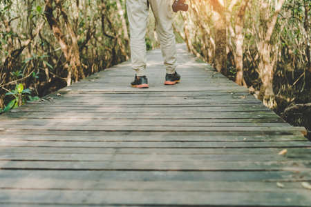 Man is walking on small wood bridge to nature walk way with sunlight flare background.の写真素材