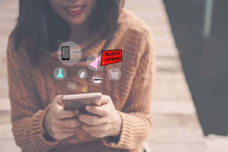 Women hand using smartphone do online selling for people shopping online in black friday with chat box, cart, dollar icons pop up. Social media maketing concept.の写真素材