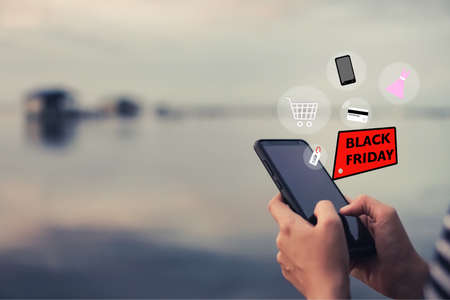 Women hand using smartphone do online selling for people shopping online in black friday with chat box, cart, dollar icons pop up. Social media maketing concept.の写真素材