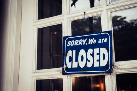 A Sign board of sorry we are closed hang on door of business shop with nature green background