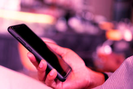 Woman hand using smartphone and laptop with cafe shop colorful highlight shade to object beautiful background. Business, financial, trade stock maket and social network concept.の写真素材