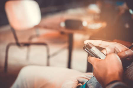 Woman hand using smartphone and laptop with cafe shop colorful highlight shade to object beautiful background. Business, financial, trade stock maket and social network concept.の写真素材