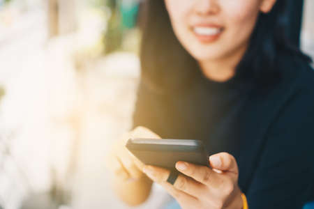Woman hand using smartphone and laptop with cafe shop colorful highlight shade to object beautiful background. Business, financial, trade stock maket and social network concept.の写真素材