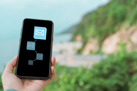 Woman hand using smartphone and it's show email recieve notification icon pop up on screen of mobile phone. Business communication  technology concept.の写真素材