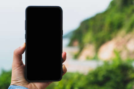 Woman hand using smartphone with nature green  beautiful background. Business, financial, trade stock maket and social network concept.の写真素材