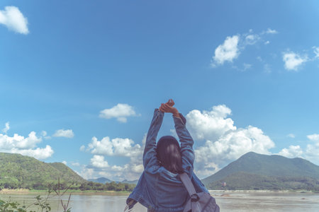 Woman rise hands up to sky freedom concept with blue sky and summer field background.