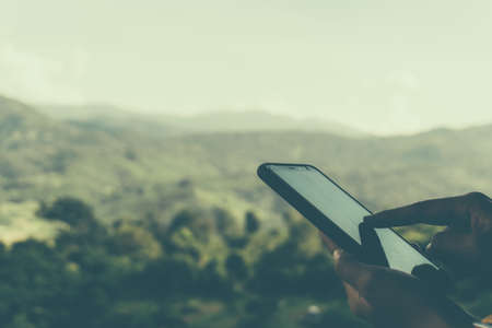 Woman hand using smartphone with nature green  beautiful background. Business, financial, trade stock maket and social network concept.の写真素材