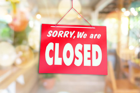 A Sign board of sorry we are closed hang on door of business shop with nature green background