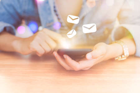 Woman hand using smartphone with email  icon pop up recieve and send notification on screen of mobile phone. Business communication technology concept.の写真素材