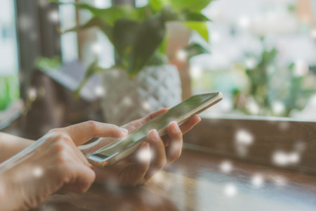Woman hand using smartphone with cafe shop colorful beautiful bokeh background. Business, financial,...