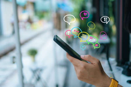 Woman hand using smartphone with chat icon background. Business communication social network concept.の写真素材