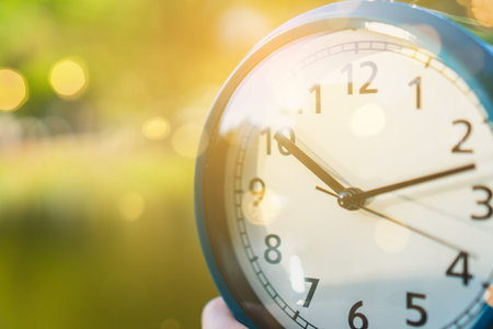 Selective focus of alarm clock with nature bokeh background.