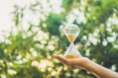 Small hourglass show time is flowing on old wood grunge texture background.の写真素材