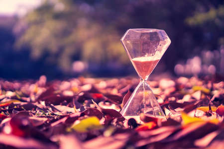 Small hourglass show time is flowing on old wood grunge texture background.の写真素材