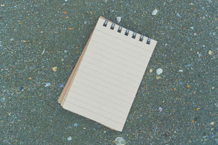 Small white notebook on sand at beautiful beach sea texture background.の写真素材