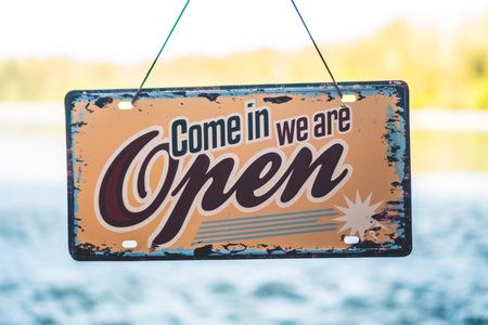 A business sign that says â€˜Openâ€™ on sand at beautiful beach background.