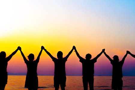 A group of women rise hands up to sky freedom concept with blue sky and summer beach sunset...