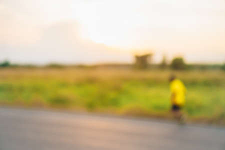 Blur people do exercise by jogging after work in park outdoor with green nature and sunlight background.の写真素材