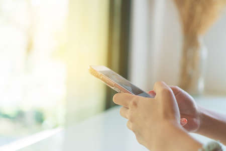 Woman hand using smartphone in cafe shop background. Business, financial, trade stock maket and social network concept.の写真素材