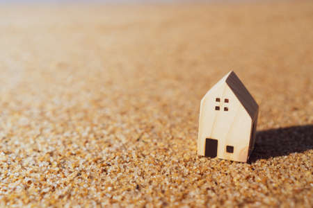 Closed up tiny home models on sand with sunlight and beach background.の写真素材