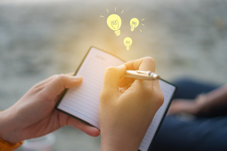 Copy space of woman hand writing down in white notebook with idea icon background.
