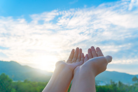 Woman hands place together like praying in front of nature green  background.の写真素材