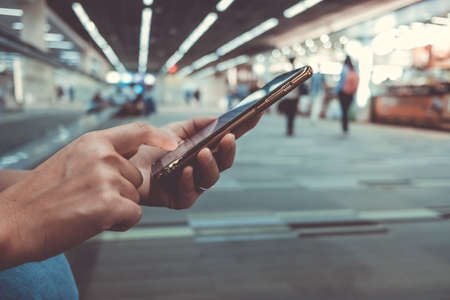 Woman hand using smartphone in hall way airport blur beautiful background. Business, financial, trade stock maket and social network concept.の写真素材