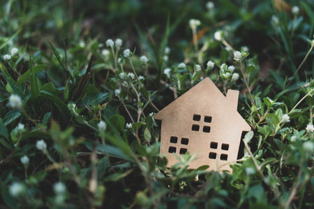 Closed up tiny home model on floor or wood board with grass background. Deam life have own house...