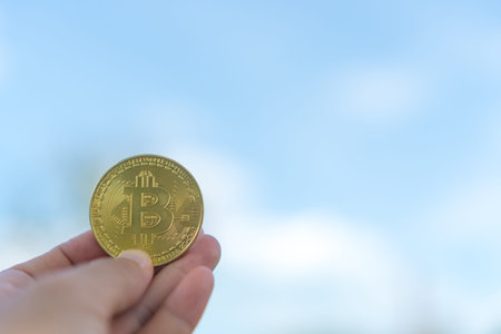 Hand hold a symbol of Bitcoins as digital money cryptocurrency with nature background with copyspace that you can put text on.の写真素材