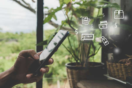 Women hand using smartphone do online selling for people shopping online in black friday with chat box, cart, dollar icons pop up in cafe shop background. Social media maketing concept.の写真素材