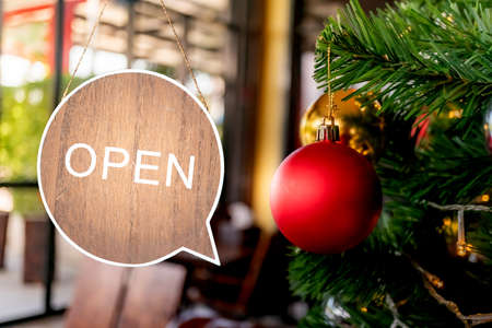 A business sign that says Open hang on cafe glass door or restaurant at entrance in Christmas and New year holiday coming. Vintage color tone style.の写真素材