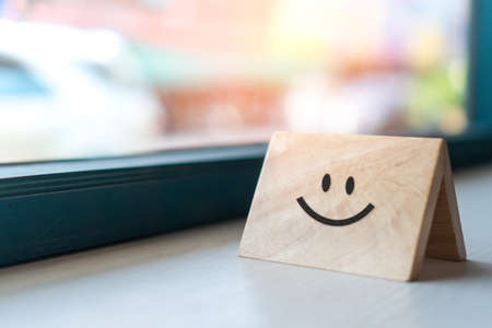 Smiley face icon on wood sign board. Optimistic person or people feeling inside and service rating, satisfaction concept in business.の写真素材