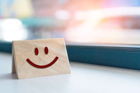 Smiley face icon on wood sign board. Optimistic person or people feeling inside and service rating, satisfaction concept in business.の写真素材