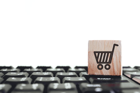 Closed up shopping cart icon on wood cube on computer keyboard. Online shopping business technology...