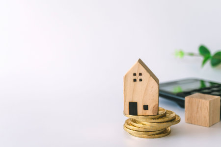 Mini house model on gold coin with clean white copyspace background. Business invest property saving...