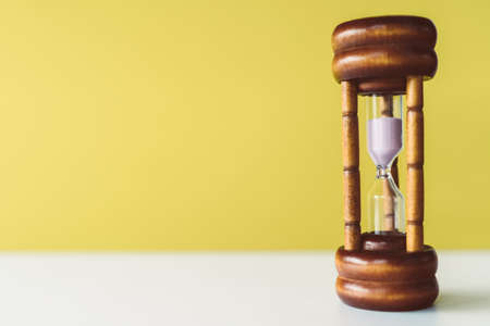 Selective focus of wooden hourglass on yellow background. Time and life concept.の写真素材