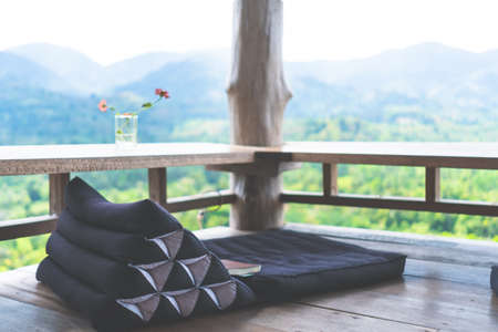 Vintage thai style floor seat around with wood table and green nature trees mountain view background. Beautiful terrace of house to relax.の写真素材