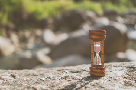 Small vintage hourglass show time is flowing never return with nature background.