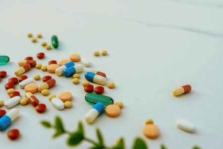 Top view of medicine tablets pour from pills bottle of marble texture white background. Health care...