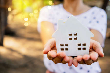 Copyspace with model of a little house that woman holds it background. Dream family life concept.の写真素材