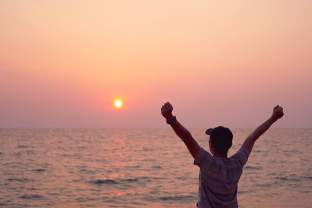 Man rise hands up to sky freedom concept with sunset sky and summer beach background.