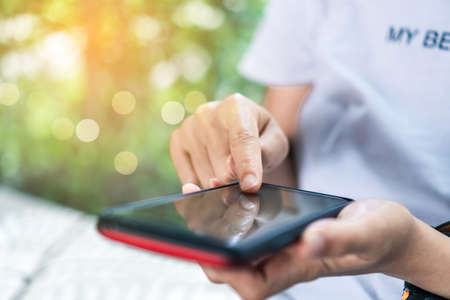 Womanhand using smartphone to do work business, social network, communication in public cafe work space area.の写真素材