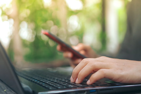 Woman hand using laptop or smartphone to work study on work desk with clean nature background...