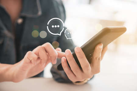 Women hand using smartphone typing, chatting conversation in chat box and icons social media app pop up. maketing technology background concept.の写真素材