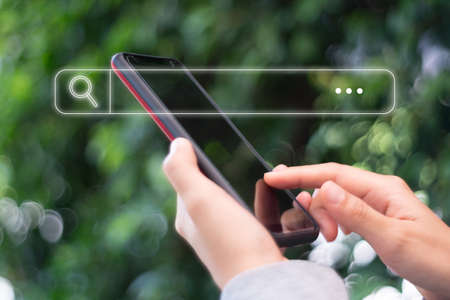 People hand using mobile phone or smartphone searching for information in internet online society web with search box icon and copyspace.の写真素材