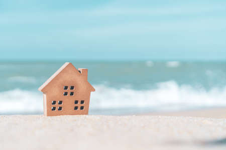 Model of a little house on sand with nature beach background. Dream life concept.の写真素材